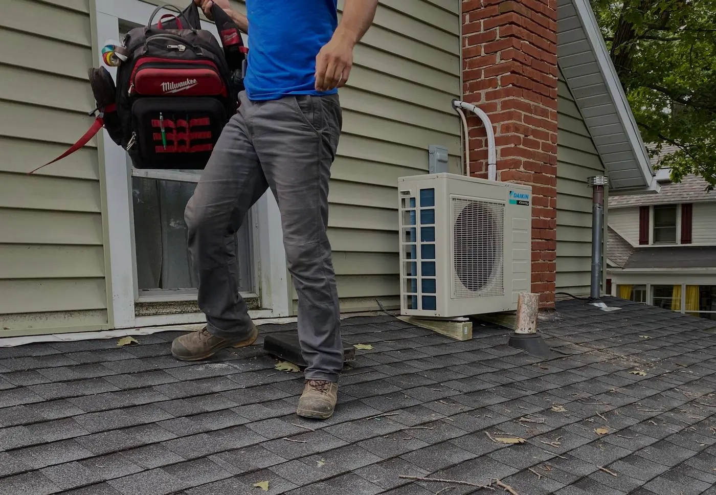 A Brimmer technician walking a roof past a newly installed mini-split unit